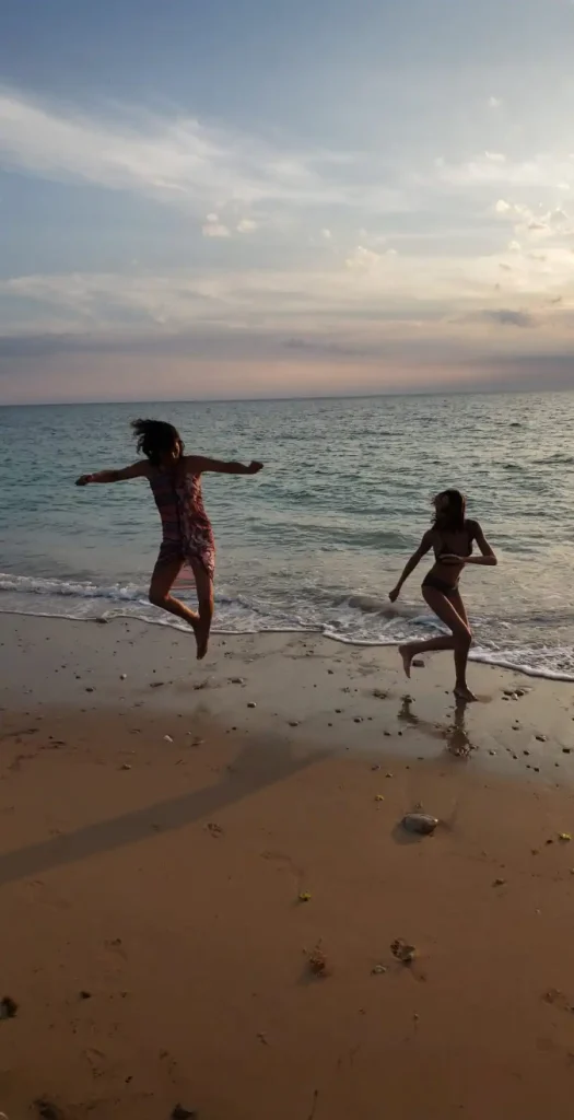 Deux filles sur une plage en plein coucher de soleil, illustrant l'énergie que donne le processus du coaching